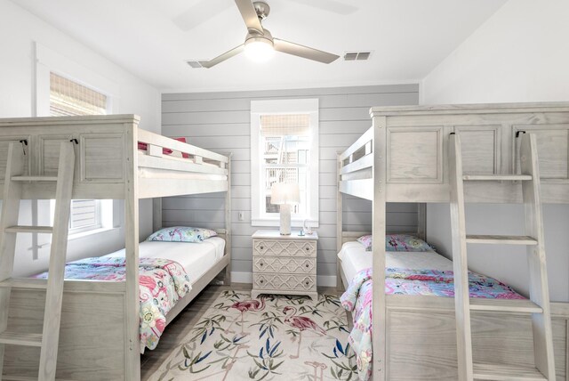 bedroom featuring wooden walls, hardwood / wood-style floors, and ceiling fan