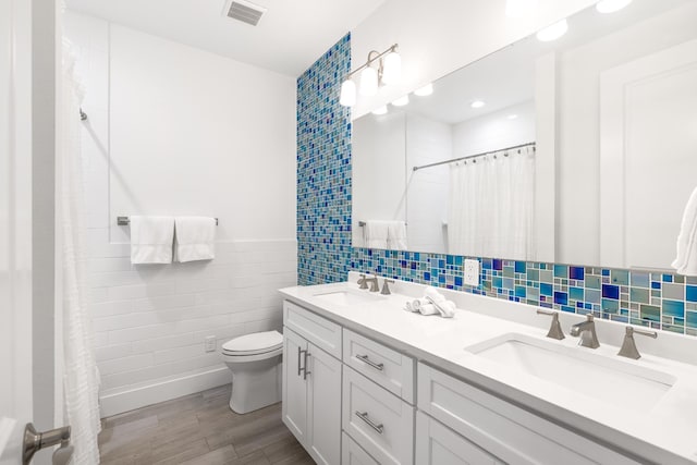 bathroom featuring tile walls, visible vents, a sink, and toilet