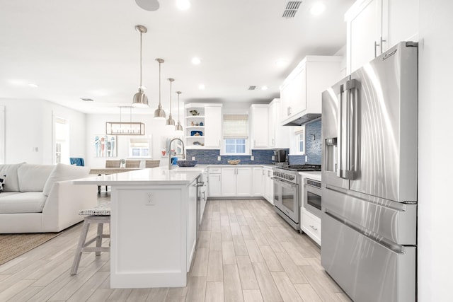 kitchen featuring visible vents, appliances with stainless steel finishes, a sink, open shelves, and open floor plan