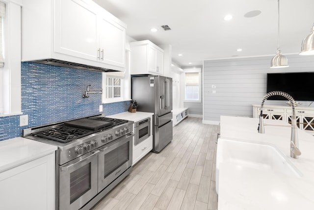kitchen with light countertops, white cabinetry, a sink, wood tiled floor, and high quality appliances