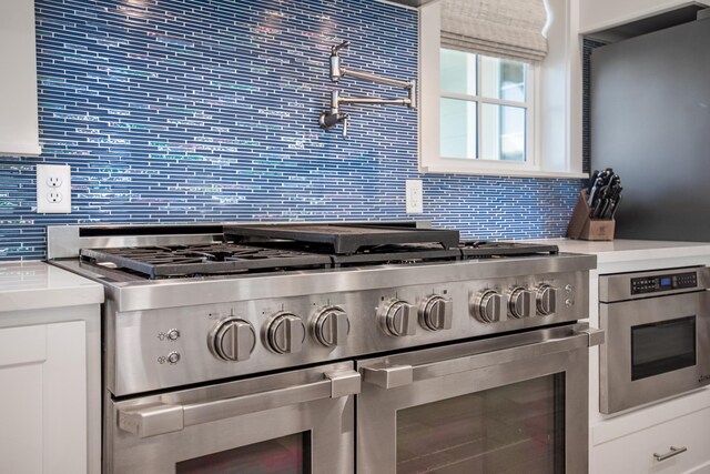 kitchen with decorative backsplash, stainless steel appliances, and white cabinets