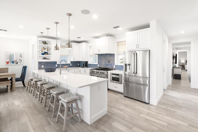 kitchen with pendant lighting, sink, a breakfast bar area, high end appliances, and kitchen peninsula