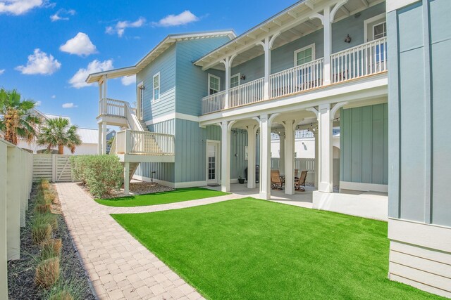 back of property featuring a yard, a patio area, and a balcony