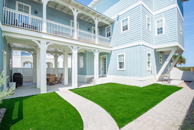 back of house featuring a balcony, a patio area, and a lawn