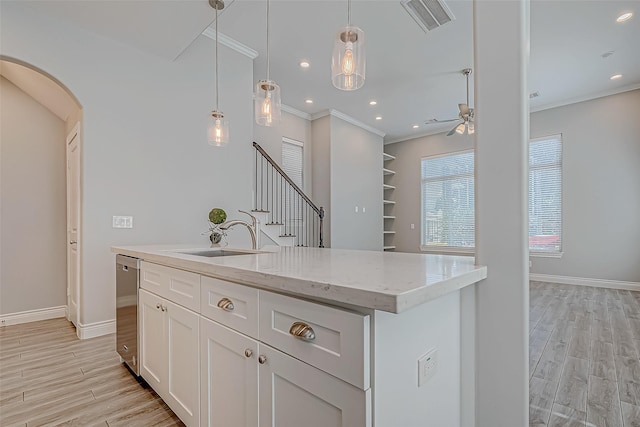 kitchen featuring a kitchen island with sink, sink, light hardwood / wood-style flooring, stainless steel dishwasher, and white cabinetry