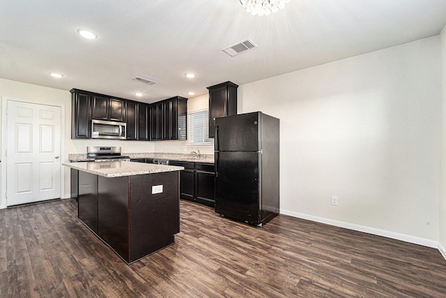 kitchen with dark wood-type flooring, stainless steel appliances, sink, and a center island