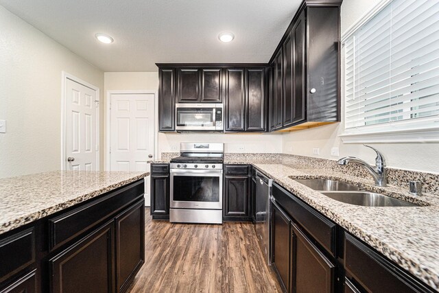 kitchen featuring dark wood-type flooring, sink, light stone counters, and stainless steel appliances