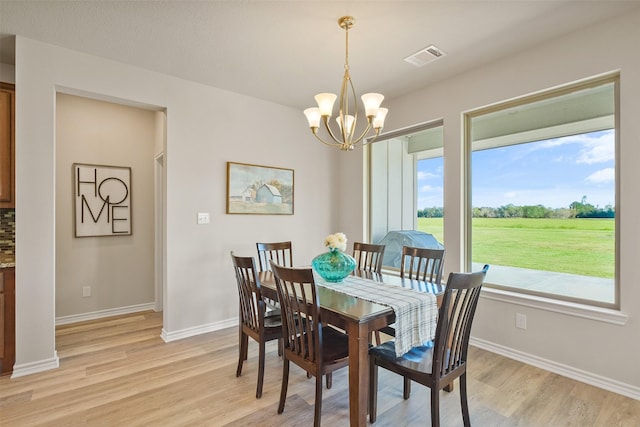 dining area with light hardwood / wood-style floors and a notable chandelier