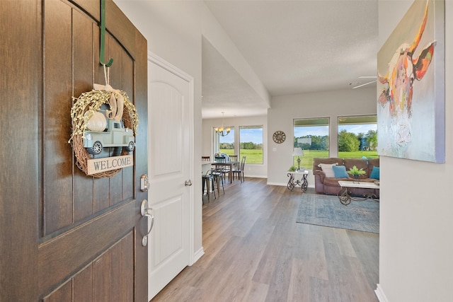 entryway with light hardwood / wood-style floors and a notable chandelier