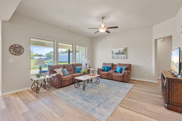 living room with ceiling fan, light hardwood / wood-style floors, and a textured ceiling