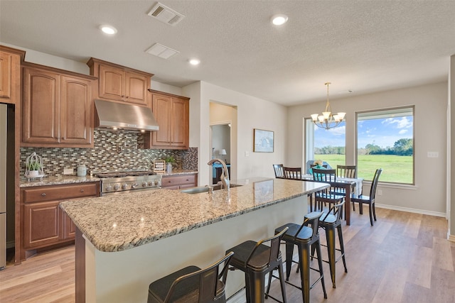 kitchen with sink, a notable chandelier, decorative light fixtures, a center island with sink, and appliances with stainless steel finishes