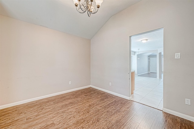 spare room with light hardwood / wood-style flooring, an inviting chandelier, and lofted ceiling