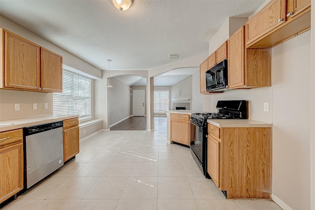 kitchen featuring hanging light fixtures, light tile patterned floors, black appliances, and a textured ceiling