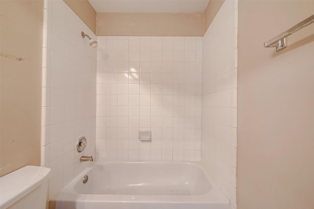 bathroom with tiled shower / bath combo and toilet