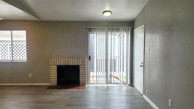 unfurnished living room with hardwood / wood-style flooring and a brick fireplace