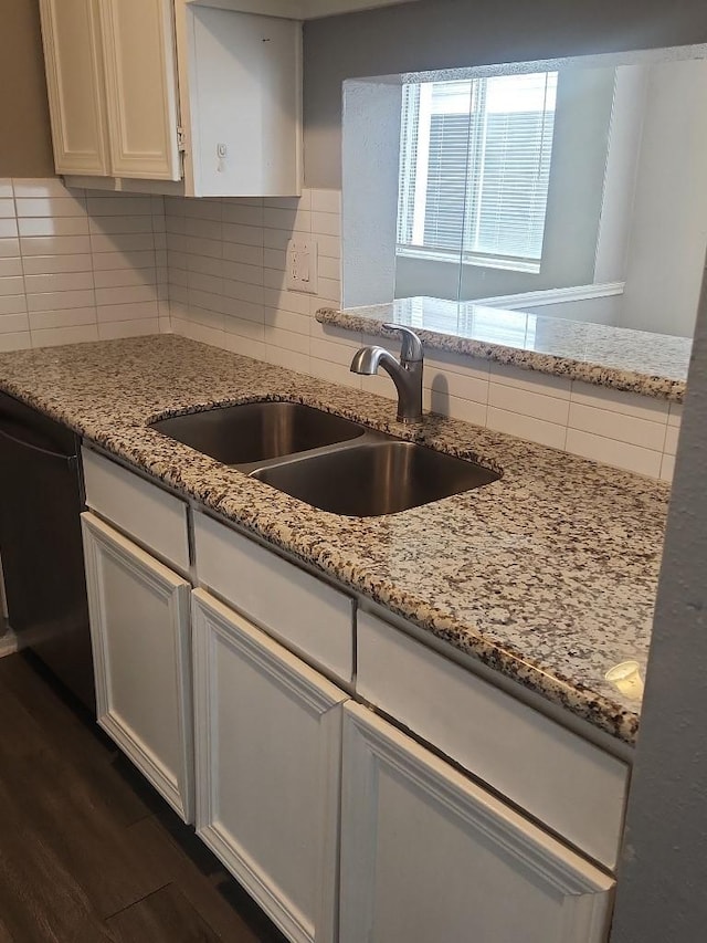 kitchen with light stone countertops, sink, black dishwasher, backsplash, and white cabinets