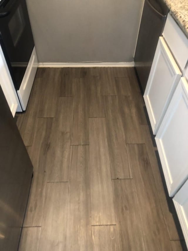 details featuring light stone counters, white cabinetry, dark wood-type flooring, and stove