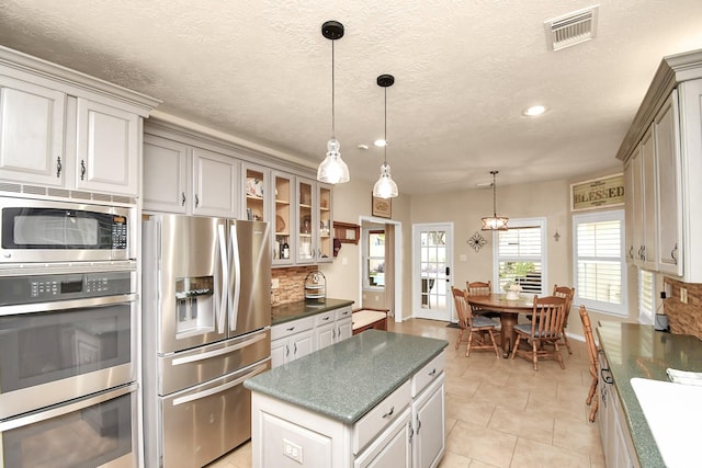 kitchen featuring pendant lighting, decorative backsplash, a center island, and stainless steel appliances