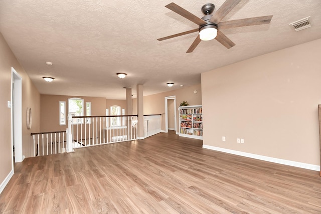 empty room featuring ceiling fan, a textured ceiling, and light hardwood / wood-style flooring