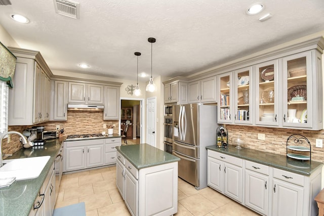 kitchen featuring pendant lighting, sink, appliances with stainless steel finishes, tasteful backsplash, and a kitchen island