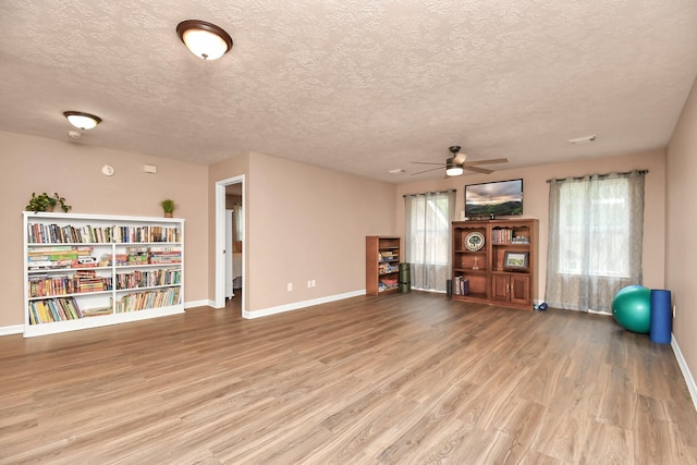 exercise room featuring hardwood / wood-style floors, ceiling fan, and a textured ceiling