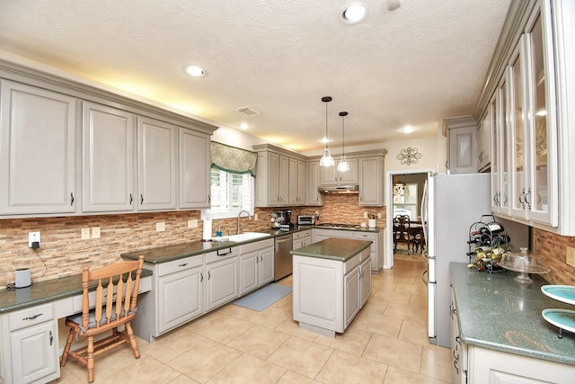 kitchen with stainless steel appliances, sink, pendant lighting, a center island, and light tile patterned flooring