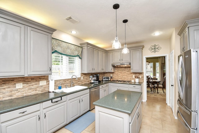 kitchen with backsplash, stainless steel appliances, sink, gray cabinets, and a kitchen island