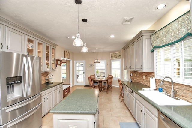 kitchen with sink, a center island, backsplash, decorative light fixtures, and appliances with stainless steel finishes