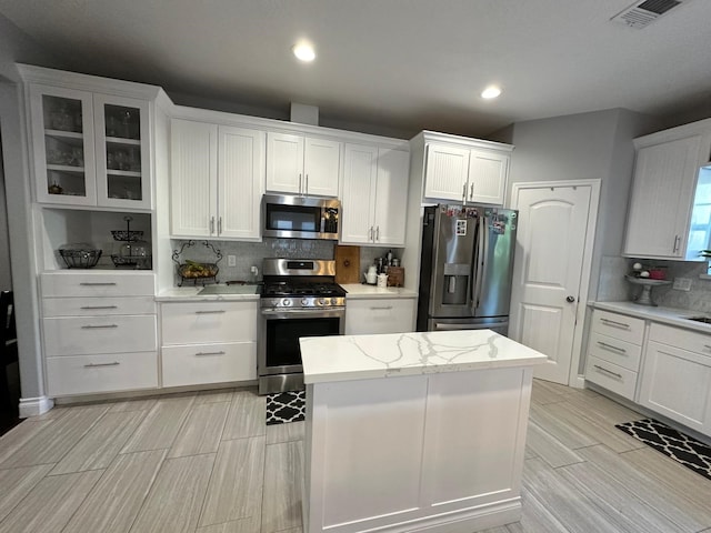 kitchen featuring white cabinets, backsplash, and appliances with stainless steel finishes