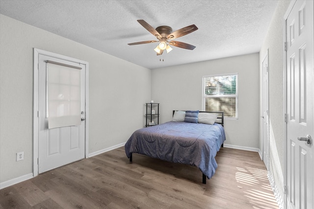 bedroom featuring ceiling fan, hardwood / wood-style floors, and a textured ceiling