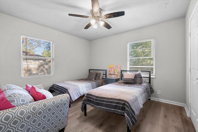 bedroom with wood-type flooring, a textured ceiling, multiple windows, and ceiling fan