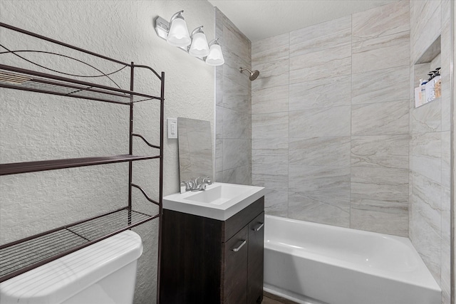 full bathroom featuring a textured ceiling, vanity, tiled shower / bath combo, and toilet