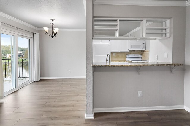 kitchen featuring light wood-type flooring, white appliances, pendant lighting, a chandelier, and white cabinetry