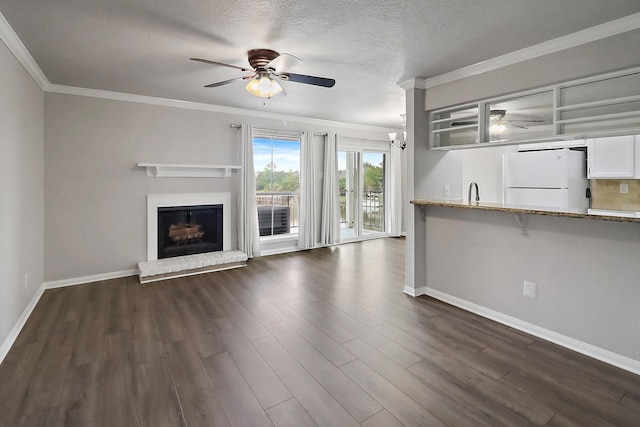 unfurnished living room featuring a textured ceiling, crown molding, dark hardwood / wood-style flooring, and a fireplace