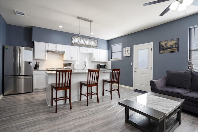 kitchen with white cabinetry, pendant lighting, light stone countertops, and appliances with stainless steel finishes