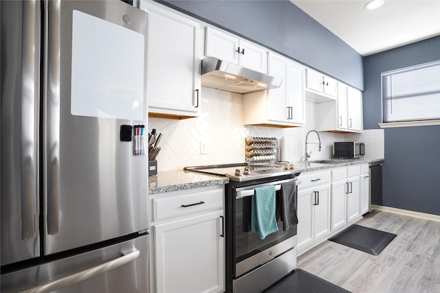 kitchen featuring light stone countertops, white cabinetry, sink, stainless steel appliances, and light hardwood / wood-style flooring