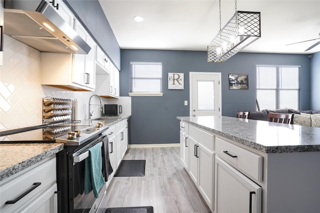 kitchen featuring white cabinets, stainless steel electric stove, a healthy amount of sunlight, and range hood