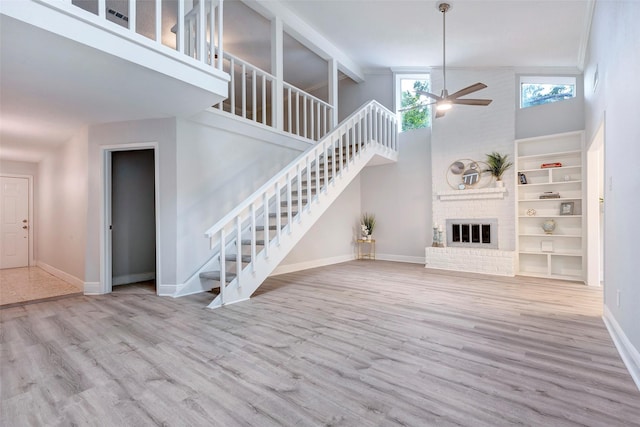 unfurnished living room with high vaulted ceiling, light hardwood / wood-style flooring, ceiling fan, and a fireplace