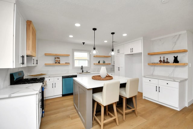 kitchen featuring dishwasher, a center island, white cabinetry, sink, and black range with gas stovetop