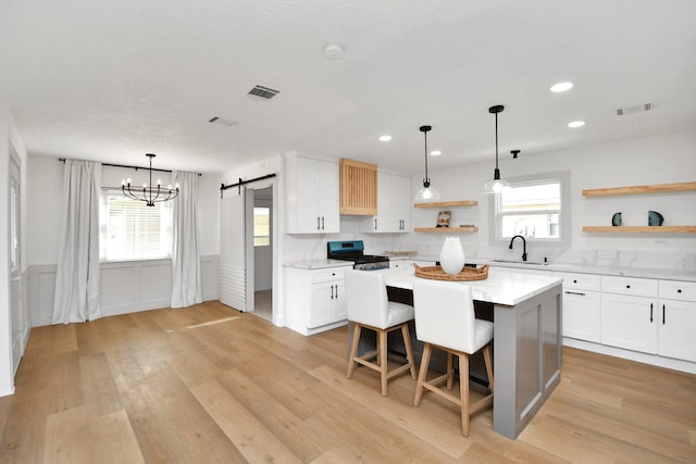 kitchen featuring a barn door, a kitchen island, sink, white cabinetry, and stainless steel electric range oven