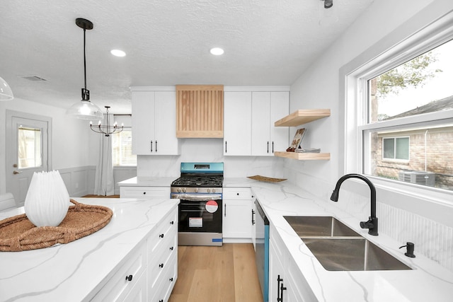 kitchen with decorative light fixtures, sink, white cabinetry, stainless steel appliances, and light stone counters