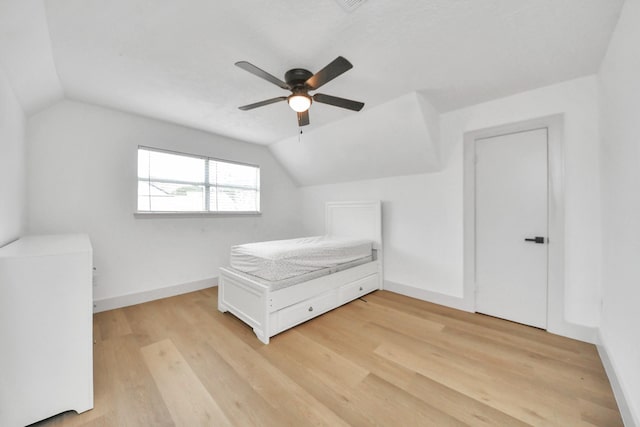 unfurnished bedroom with ceiling fan, lofted ceiling, and light wood-type flooring