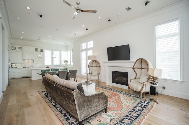 living room with ceiling fan, light hardwood / wood-style floors, sink, and crown molding