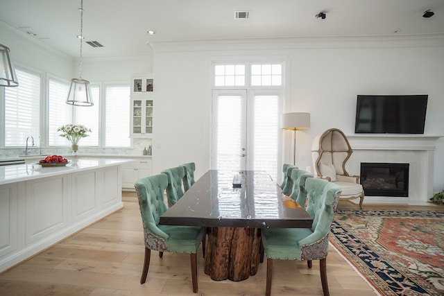 dining area featuring sink, ornamental molding, and light wood-type flooring