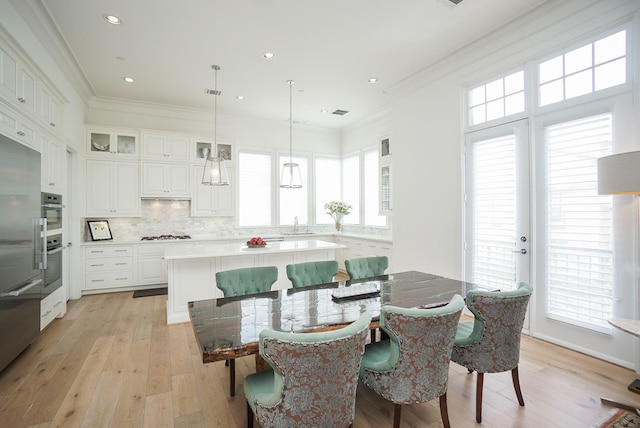 dining room featuring plenty of natural light, sink, crown molding, and light hardwood / wood-style flooring