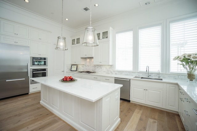 kitchen with a center island, white cabinets, stainless steel appliances, and sink