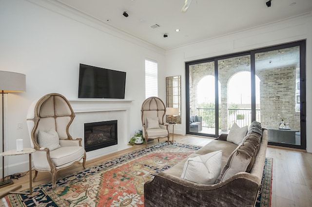 living room with wood-type flooring, ornamental molding, and a healthy amount of sunlight