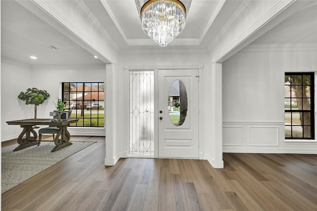 foyer entrance with ornamental molding, hardwood / wood-style flooring, a healthy amount of sunlight, and a notable chandelier