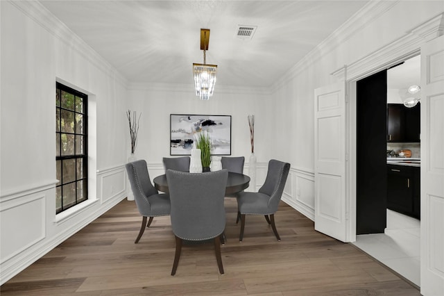 dining area with a chandelier, wood-type flooring, and ornamental molding