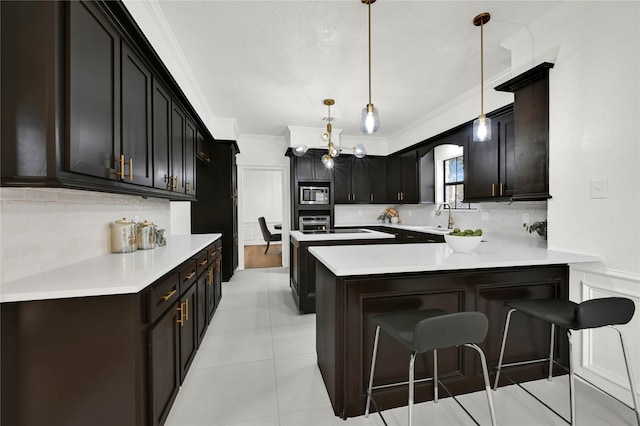 kitchen with stainless steel microwave, tasteful backsplash, kitchen peninsula, pendant lighting, and a breakfast bar area